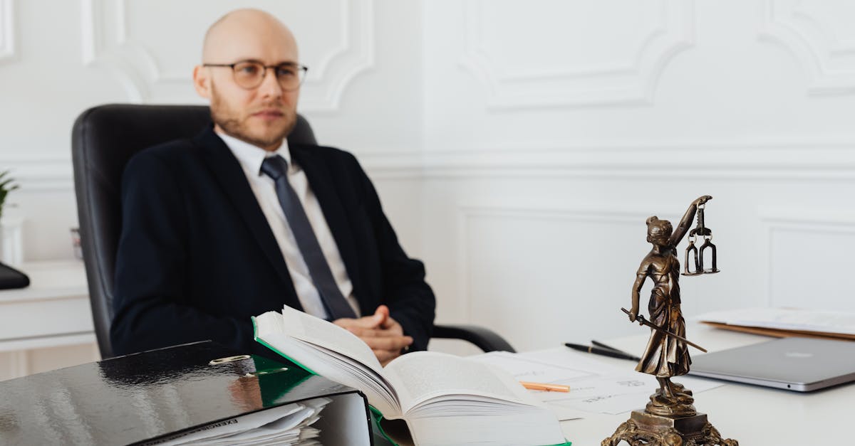 bald lawyer in office sitting with legal documents and justice statue